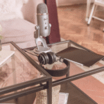 Podcast setup with microphone, headphones, and tablet on a glass table
