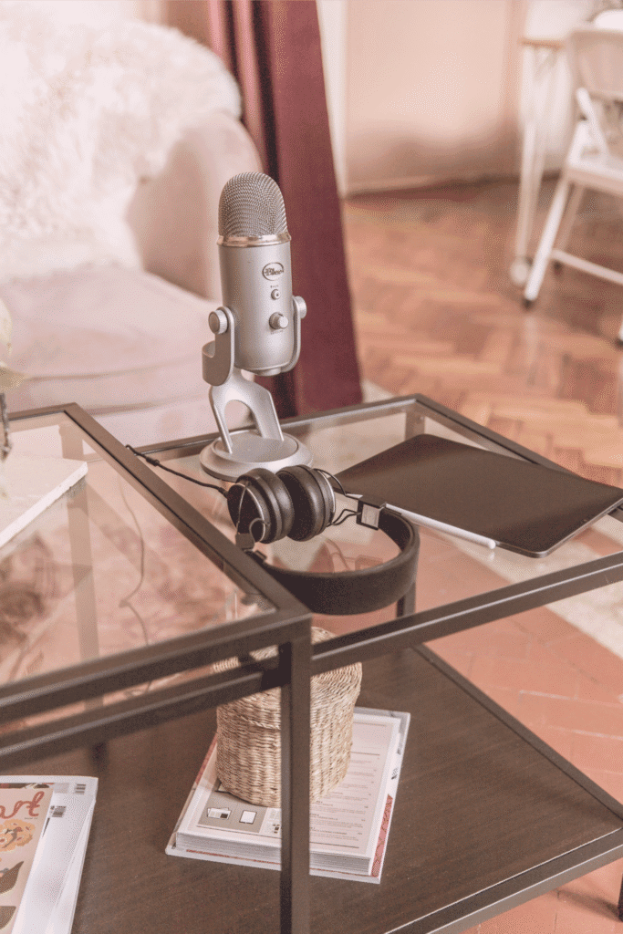 Podcast setup with microphone, headphones, and tablet on a glass table