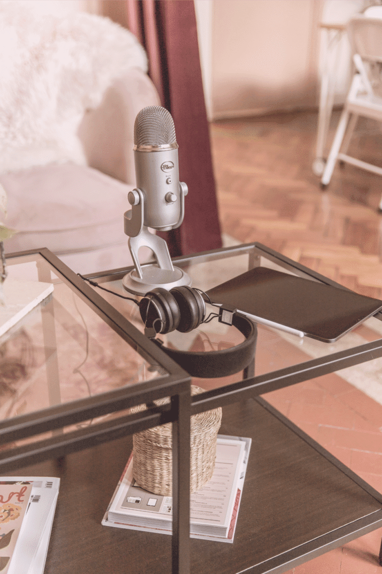 Podcast setup with microphone, headphones, and tablet on a glass table