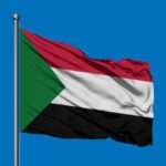 Flag of Sudan waving in the wind against deep blue sky.