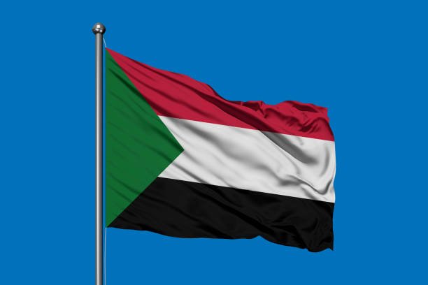 Flag of Sudan waving in the wind against deep blue sky.
